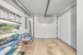 A clean, spacious garage with ample storage potential, featuring organized equipment including kayaks and paddleboards for your water adventures.