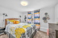 Your peaceful bedroom features cheerful yellow florals, colorful striped curtains, and thoughtful touches like bedside reading lamps for cozy evenings.