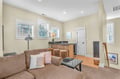 Relax in your bright, airy living space with plush seating, modern kitchen bar, and warm natural light streaming through multiple windows.