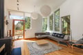 Sink into this stylish living space where natural light streams through floor-to-ceiling windows, warming the sleek furnishings and polished hardwood floors.