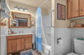 Clean, comfortable bathroom with a spacious shower, oak vanity, and thoughtful touches like grab bars for your safety and convenience.