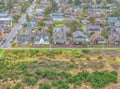 Aerial view shows charming coastal neighborhood with diverse homes and natural open space nearby.