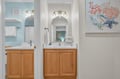 Step into your coastal-themed bathroom with dual vanities, warm wood cabinets, and charming seaside artwork that makes your daily routine feel like a beachside retreat.