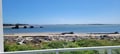 Coastal scene features sandy beach, calm blue waters, scattered driftwood, and distant rocky formations under clear skies—part of the property's scenic surroundings.